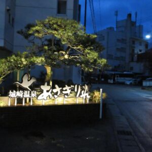 Illuminated Asagiriso entrance sign at dusk beside street and urban buildings in Hyōgo