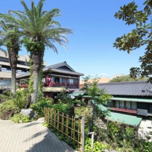Palm trees and tiled ryokan buildings at Chikurakan in Chiba, Kanto with paved garden path and greenery