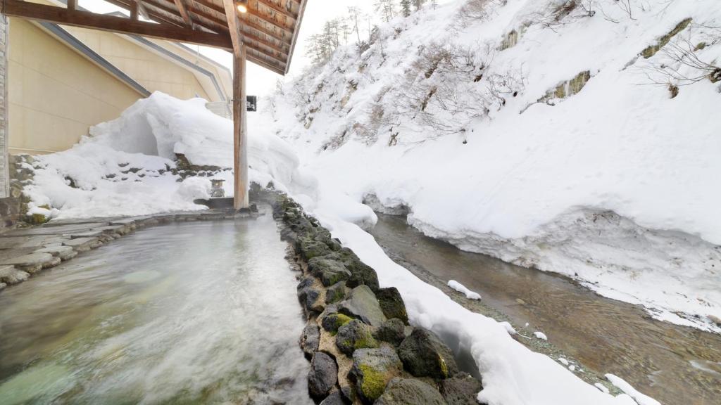 Snowy outdoor onsen at Fulsato Iwate Outdoor stone onsen bath with steam and snow banks at Fulsato ryokan, Iwate Tōhoku
