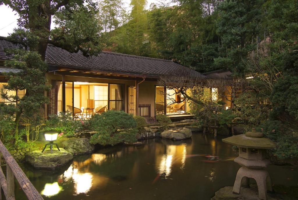 Evening garden exterior at ryokan Gyokutei Kanagawa Traditional ryokan beside reflective garden pond with stone lantern and lit shoji rooms in Kanagawa