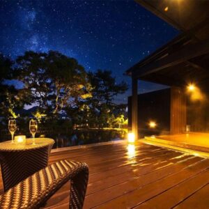Wooden outdoor onsen deck with lounge chairs under a starry sky at HOSHINO-OTO in Kyoto