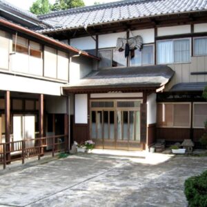 Traditional wooden facade and tiled roof with paved entrance courtyard at Hagurokan in Yamagata prefecture