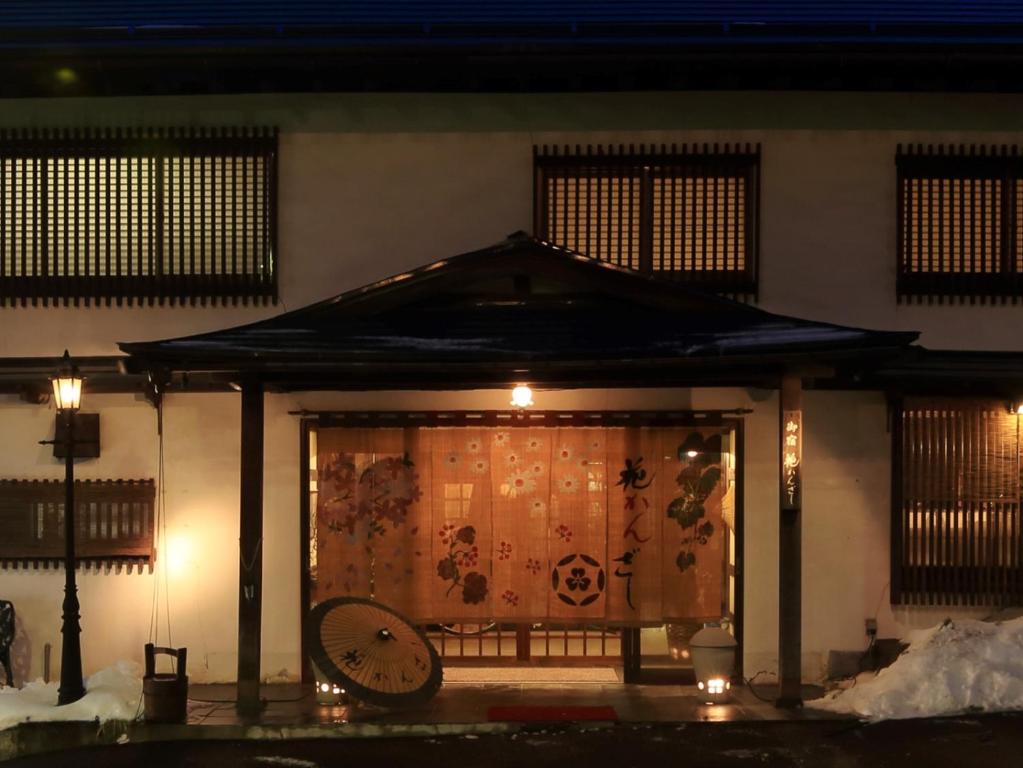 Warm lit entrance Hanakanzashi Fukushima Entrance with noren curtain, lantern glow and snow at Hanakanzashi ryokan in Fukushima