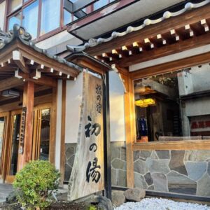 Wooden entrance with stone signboard at Hatsunoyu ryokan in Nagano