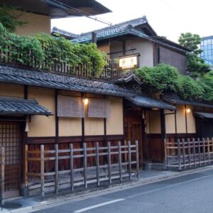 Exterior of Hiiragiya with wooden lattice, tiled roof, lanterns and greenery along a Kyoto street
