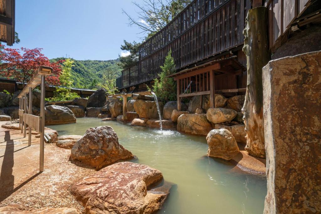 Stone outdoor onsen Hirayukan Gifu Japan Outdoor stone onsen with wooden baths and mountain backdrop at Hirayukan, Gifu, Chūbu, Japan