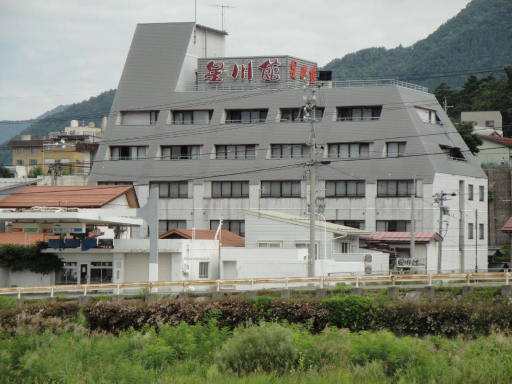 Riverside ryokan Hoshikawakan Chūbu Nagano Multi-story riverside ryokan building with signage and mountain backdrop in Nagano Chūbu region