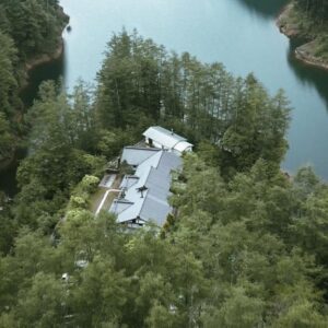 Aerial view of Hotorinite among dense forest on a lakeshore in Yamanashi, Chūbu