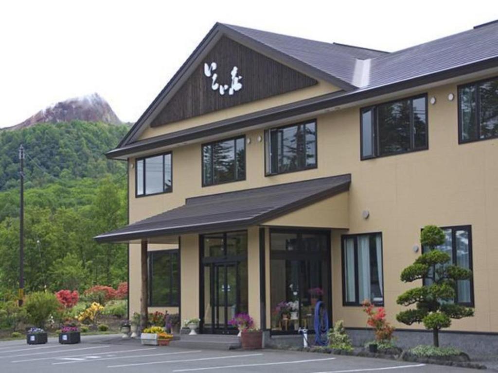 Ryokan entrance at Ikoiso Hokkaidō Exterior view of two story ryokan building and landscaped entrance with distant mountain backdrop in Hokkaidō