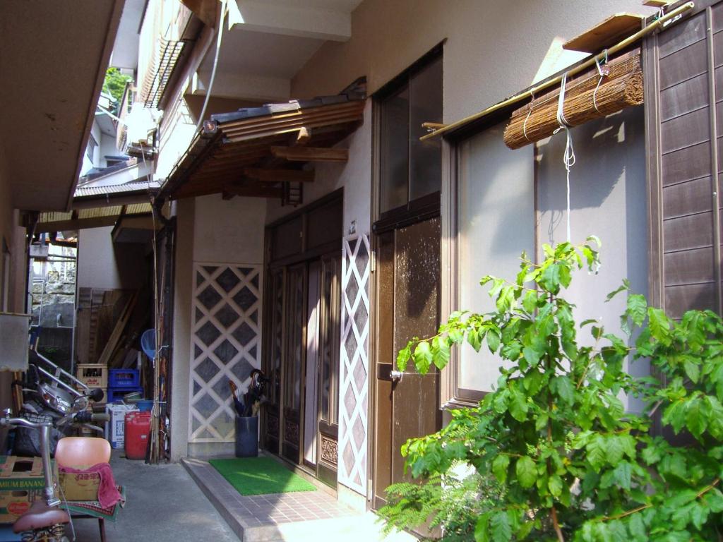 Traditional alleyway at Ishibu-so Shizuoka Narrow paved alley with wooden facades, shoji-style doors, potted greenery and straw-wrapped window coverings at Ishibu-so, Shizuoka