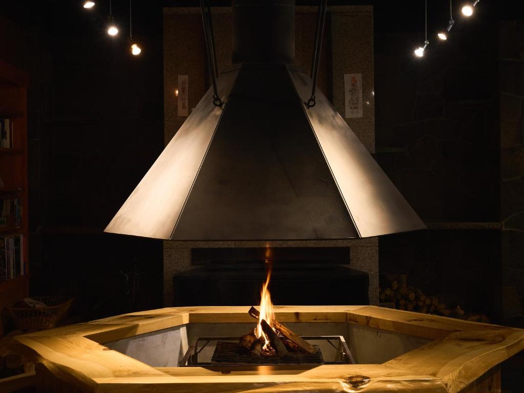 Irori Hearth at Ishinoyu Lodge Nagano Central wooden irori hearth with suspended metal hood and glowing fire at Ishinoyu Lodge in Nagano