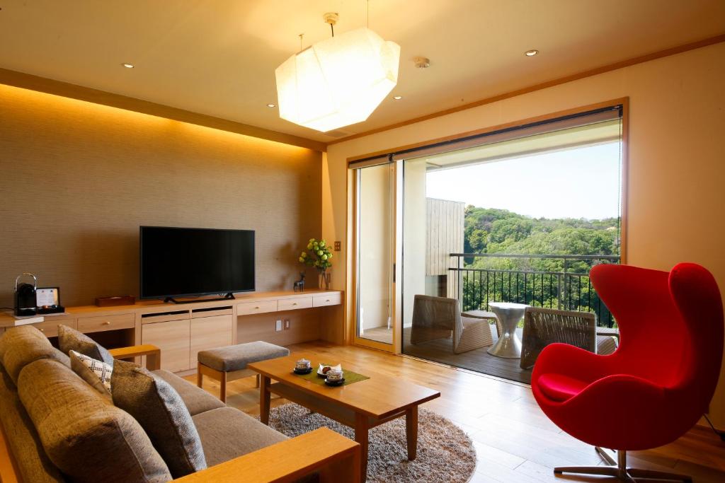 Balcony lounge with red chair Kakimotoya Nara Sofa and red armchair by balcony with TV and greenery view at Kakimotoya, Nara