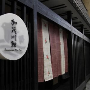 Round kanji sign and noren at Kamogawakan entrance in Kyoto