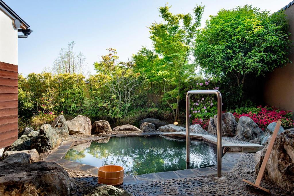 Stone garden onsen at Kannawaen Ōita Kyūshū Stone-framed outdoor onsen bath with wooden bucket and handrail at Kannawaen in Ōita, Kyūshū, Japan