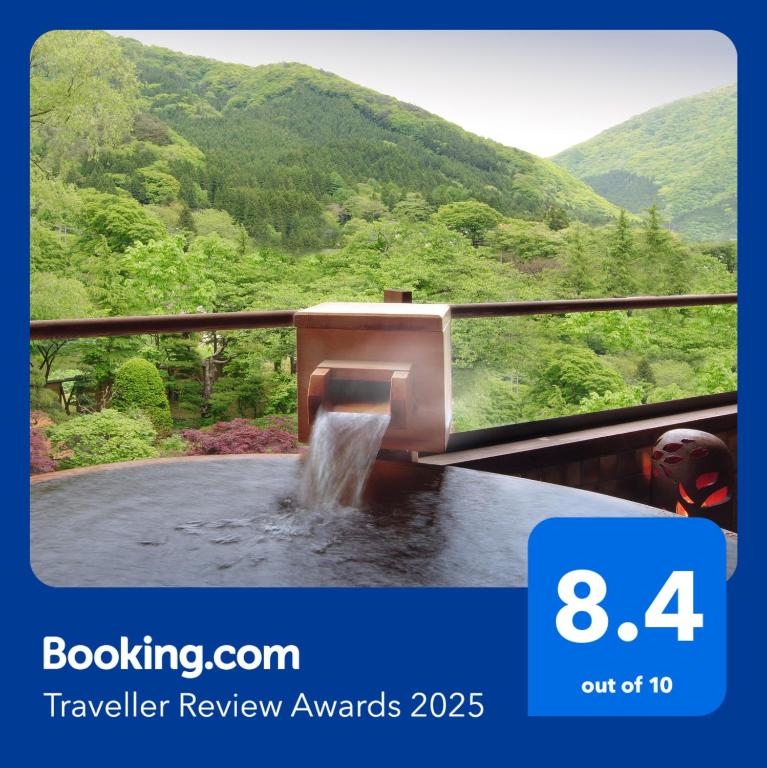 Outdoor onsen overlooking valley Kansyokan Yamagata Outdoor onsen bath with wooden spout and glass railing overlooking green mountains at Kansyokan, Yamagata