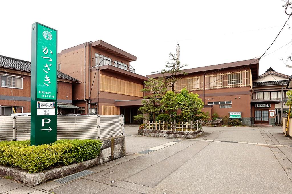 Exterior of Katsuzakikan in Ishikawa Japan Traditional multi-story wooden ryokan exterior with green signboard and small courtyard at Katsuzakikan, Ishikawa