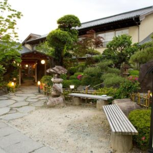 Stone path, lanterns and manicured shrubs leading to wooden ryokan entrance at Kikori, Yamanashi