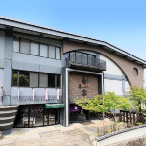 Front facade and entrance of Kikunoya with balconies and landscaped trees in Hiroshima, Chūgoku region