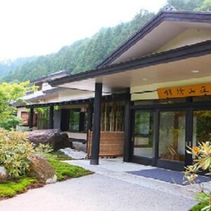 Entrance of Kinshuusanso with wooden beams, garden path and forested mountain backdrop in Gunma Kantō