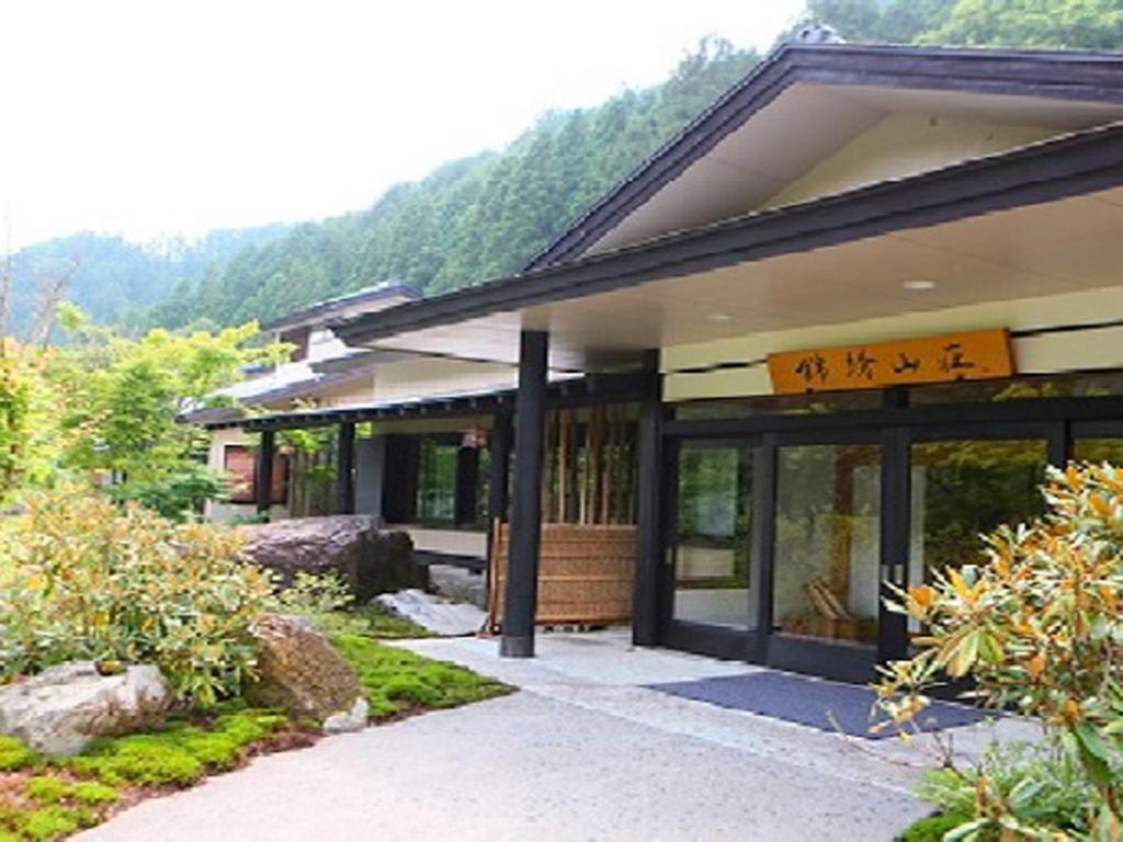 Traditional ryokan entrance Kinshuusanso Gunma Kantō Entrance of Kinshuusanso with wooden beams, garden path and forested mountain backdrop in Gunma Kantō
