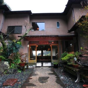 Traditional ryokan entrance with stone path, potted plants and wooden façade at Kokoronodoka in Shizuoka