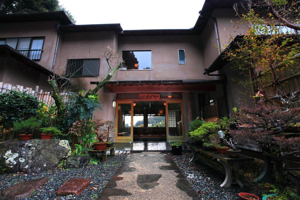 Garden entrance at Kokoronodoka Shizuoka Traditional ryokan entrance with stone path, potted plants and wooden façade at Kokoronodoka in Shizuoka