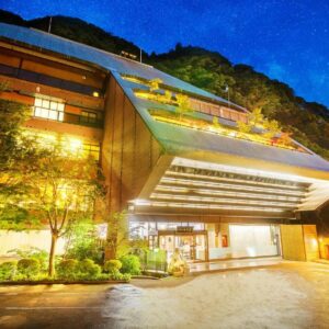 Night view of Konjakutei entrance with lit canopy and hillside backdrop