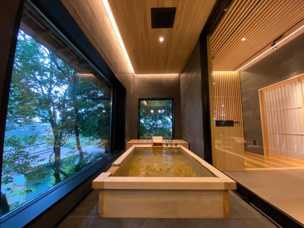 Indoor wooden bath at Kotobukitei Mie Indoor wooden bath with large window overlooking trees at Kotobukitei, Mie, Kansai