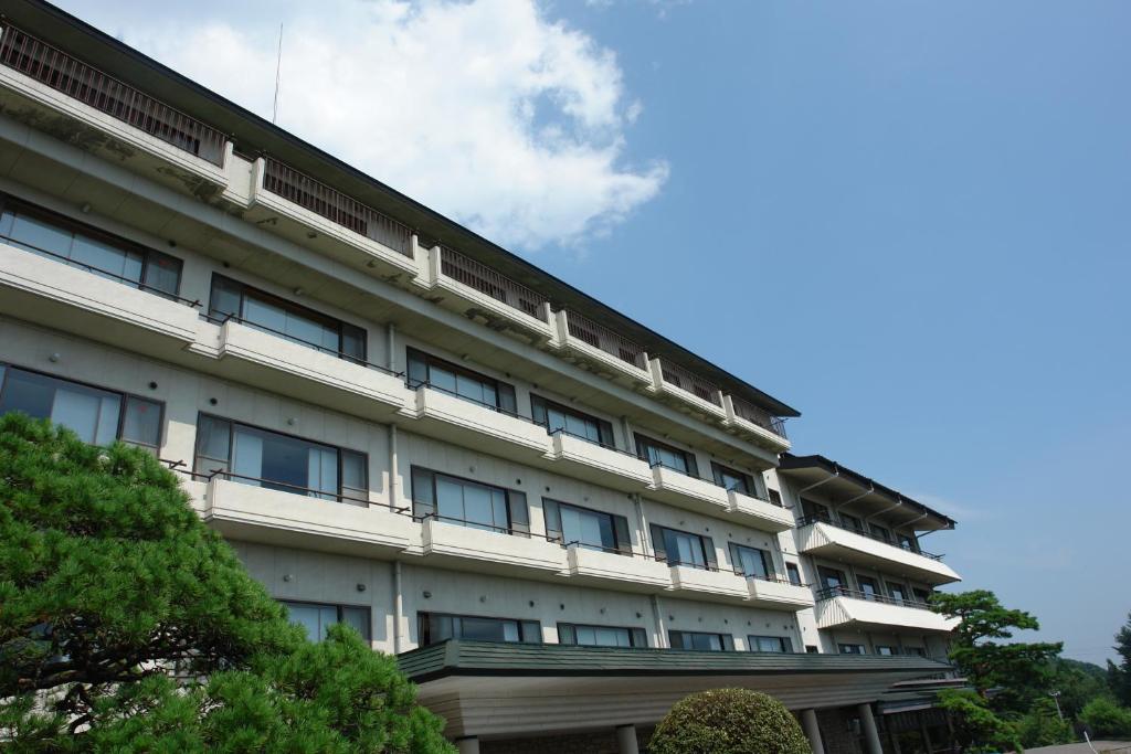 Exterior facade of Kounkaku Ryokan Fukushima Multi-story ryokan building with balconies and pine trees at Kounkaku in Fukushima Tohoku