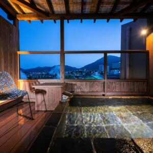 Stone open-air onsen bath with chair and town mountain view at Kunisakisou, Ōita, Kyūshū, Japan