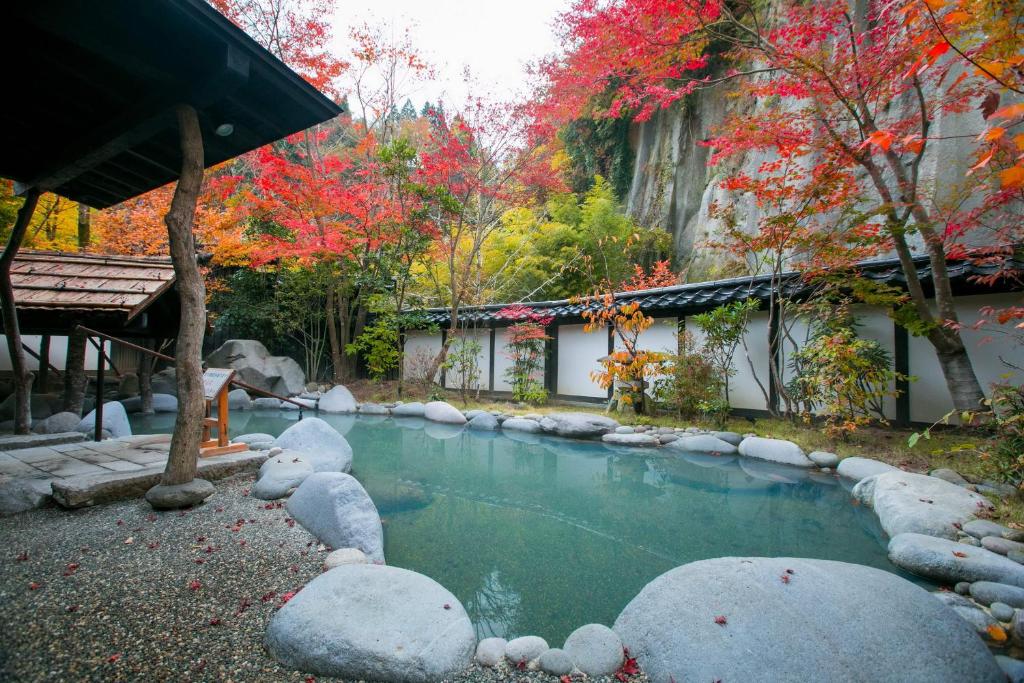 Outdoor Onsen at Kurokawa-So Kumamoto Outdoor onsen pool with red maple trees and stone edging at Kurokawa-So in Kumamoto, Kyushu