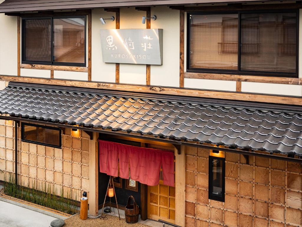 Noren Entrance at Kurosakisou Kyoto Traditional wooden ryokan entrance with red noren, tiled roof and shoji windows at Kurosakisou in Kyoto