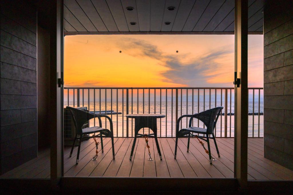 Sunset Balcony Meijikan Shizuoka Chubu Japan Wooden balcony with two chairs and small table overlooking calm ocean at sunset from Meijikan in Shizuoka