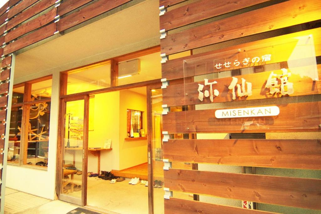 Wooden entrance at Misenkan Nara Warm-lit wooden facade and open entrance with slippers inside at Misenkan ryokan in Nara, Kansai