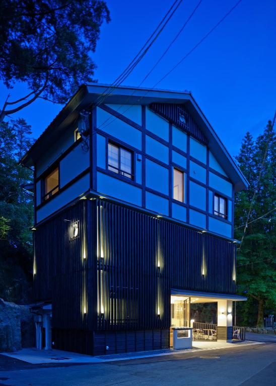 Evening exterior Mizuhasou ryokan Hiroshima Dusk exterior of three-story timber ryokan with illuminated entrance and surrounding trees in Hiroshima prefecture