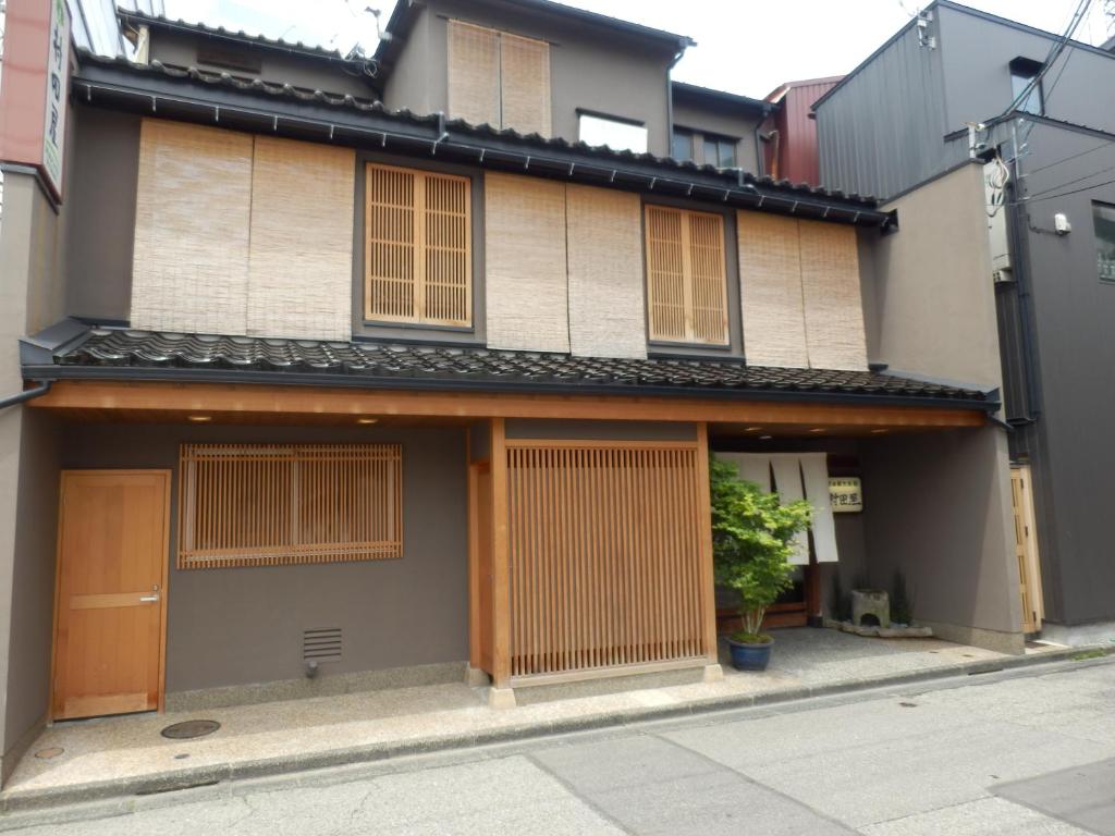 Wooden ryokan facade Murataya Ishikawa Japan Two-story traditional wooden ryokan entrance with lattice door, bamboo blinds, and potted plants on a narrow street