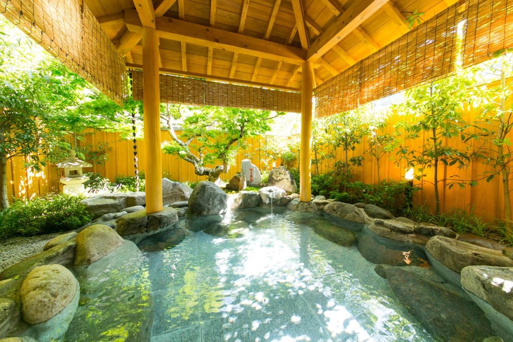 Rock onsen at Mutsumikan Gifu Stone-lined covered onsen bath with bamboo fence and greenery at Mutsumikan in Gifu