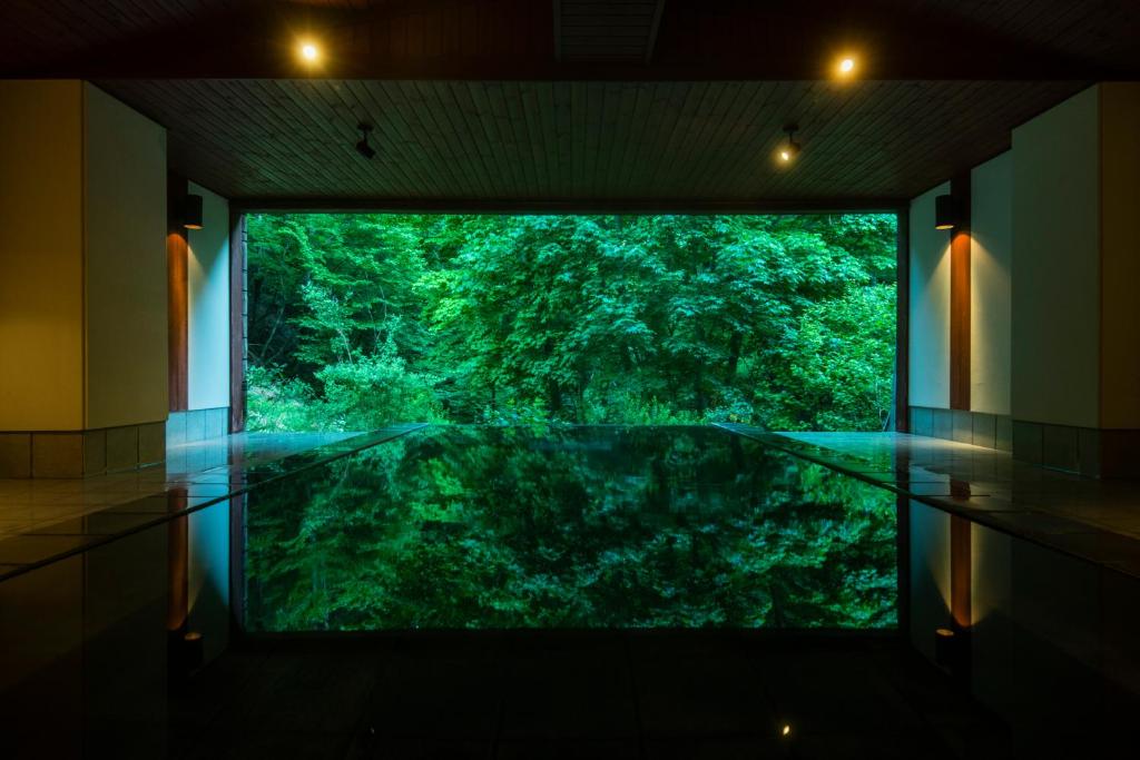 Indoor bath overlooking forest Myojinkan Nagano Reflective indoor bath framed by large window showing lush forest at Myojinkan, Nagano, Chūbu