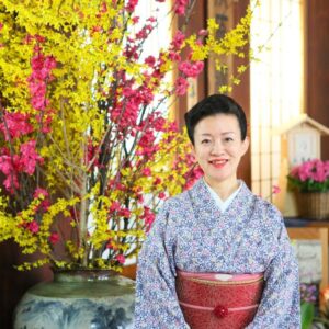 Ryokan staff in kimono by large floral arrangement at reception in Ogiwarakan, Nagano