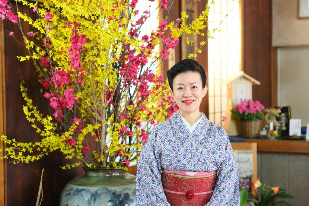 Smiling host in kimono Ogiwarakan Nagano Ryokan staff in kimono by large floral arrangement at reception in Ogiwarakan, Nagano
