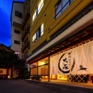 Lit traditional noren curtains at Omori ryokan entrance on an evening street in Gunma, Kantō, Japan