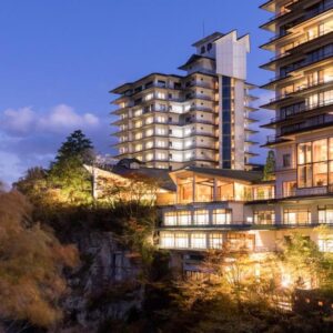 Illuminated Sakan ryokan building on a cliff above a wooded gorge in Miyagi, Tōhoku at dusk