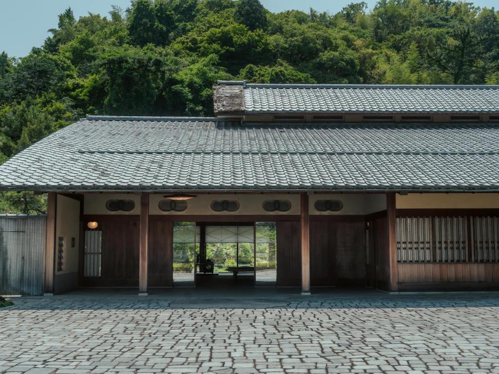 Traditional entrance facade Sanyo-so Shizuoka Cobblestone courtyard and wooden entrance of Sanyo-so with tiled roof and forested hillside in Shizuoka, Chūbu