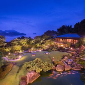 Evening illuminated Japanese garden with pond, stone lanterns and seaside view at Sekitei, Hiroshima, Japan