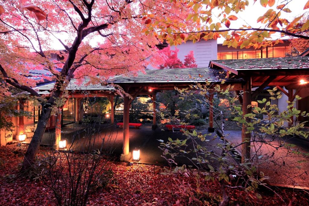 Autumn maple courtyard at Senkyo Gunma Lit courtyard with red maple leaves, wooden walkway and traditional ryokan exterior at dusk in Gunma