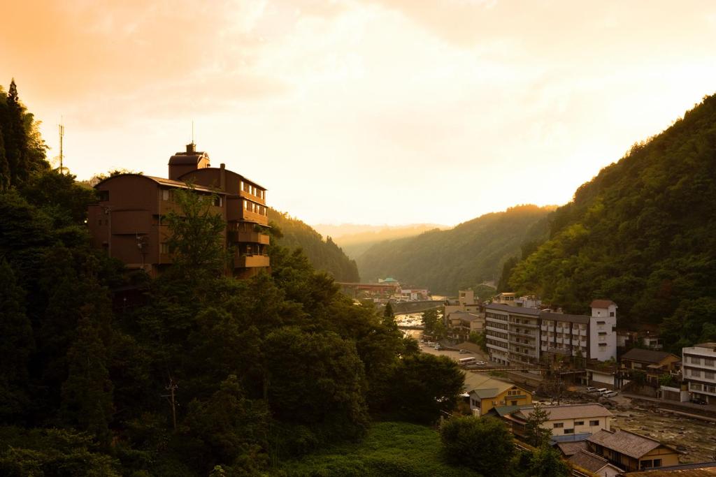 Hillside Ryokan Shinshiyo Ōita Shinshiyo buildings on a forested hillside overlooking a river valley at golden hour in Ōita, Kyūshū