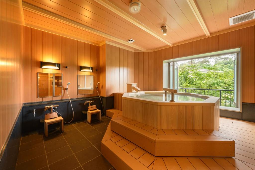 Wooden soaking tub at Shintomi-tei Miyagi Indoor wooden soaking tub with stools and large window overlooking greenery at Shintomi-tei, Miyagi