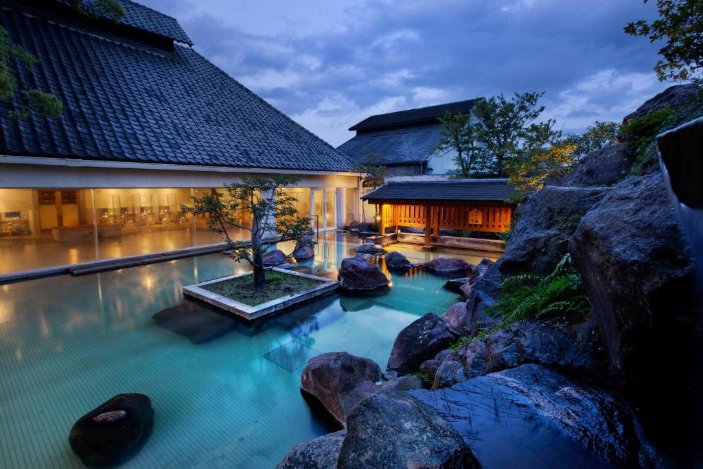 Evening onsen courtyard at Shiragiku Ōita Outdoor onsen bath with rock garden and illuminated traditional buildings at dusk, Shiragiku, Ōita
