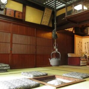 Traditional tatami room with sunken irori hearth, hanging kettle, floor cushions and wooden shoji interiors at Shitanda, Gifu