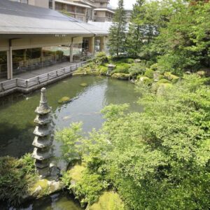Traditional garden pond with stone pagoda lantern and wooden veranda at Suimeikan in Chūbu, Gifu, Japan